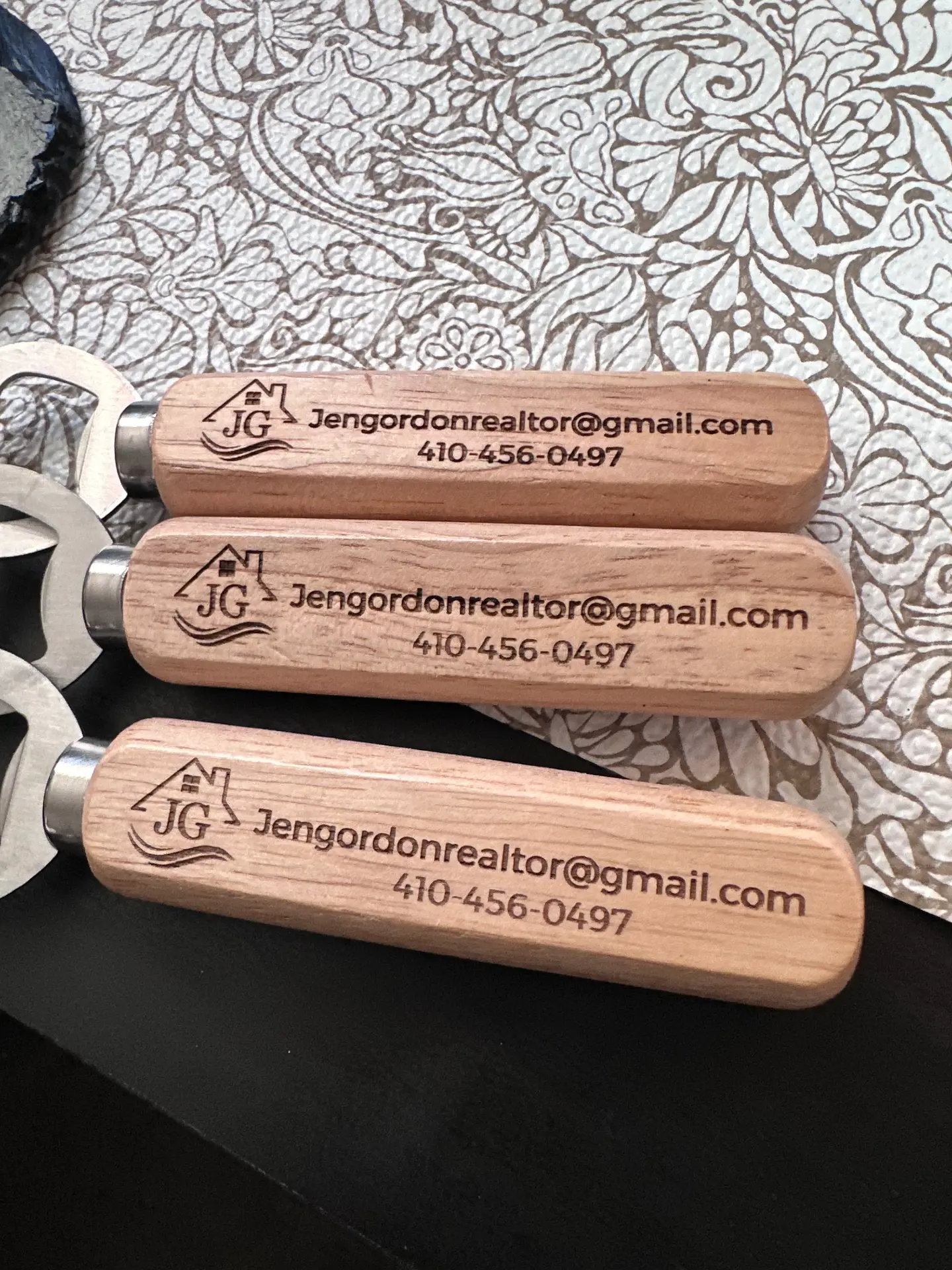 Three cherry-handled bottle openers engraved with a realtor's email and phone number