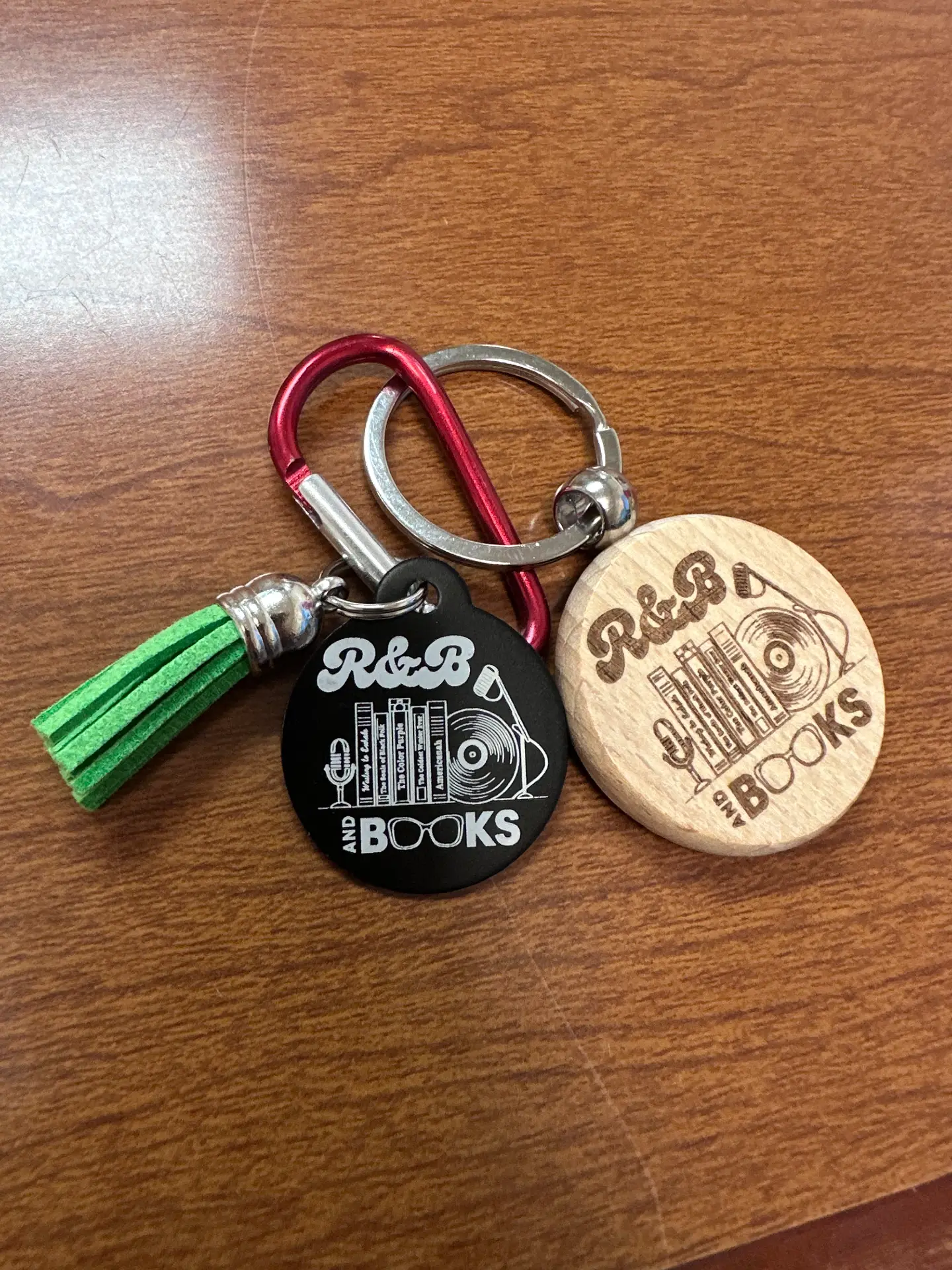 Black metal and wood round keychains engraved with the R&B and Books logo