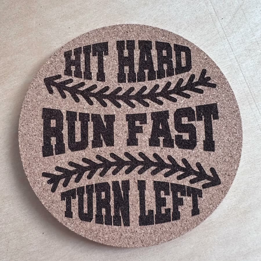 Round cork coaster engraved: Hit hard, run fast, turn left, with baseball stitching