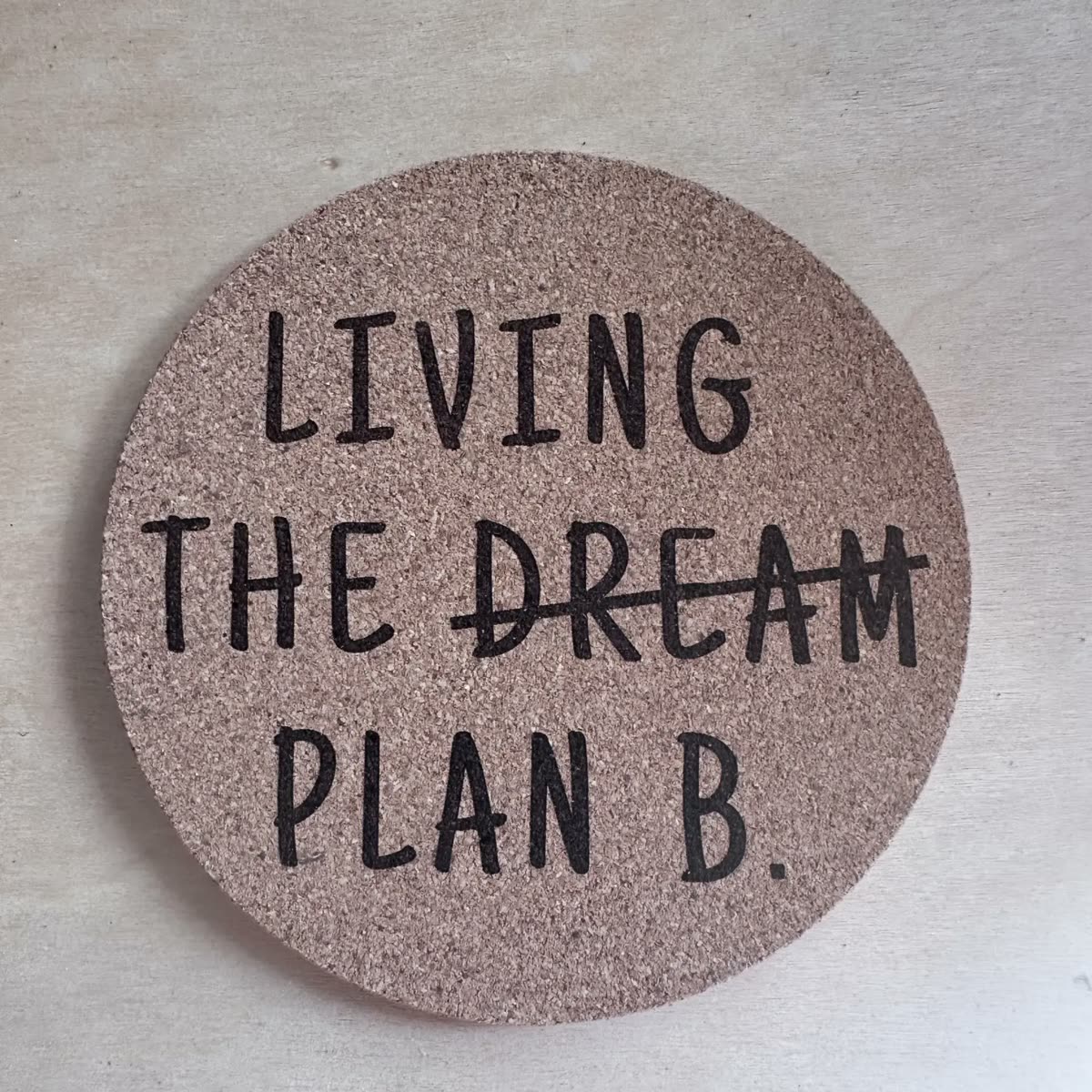 Round cork coaster engraved: Living the dream, dream crossed out, plan B