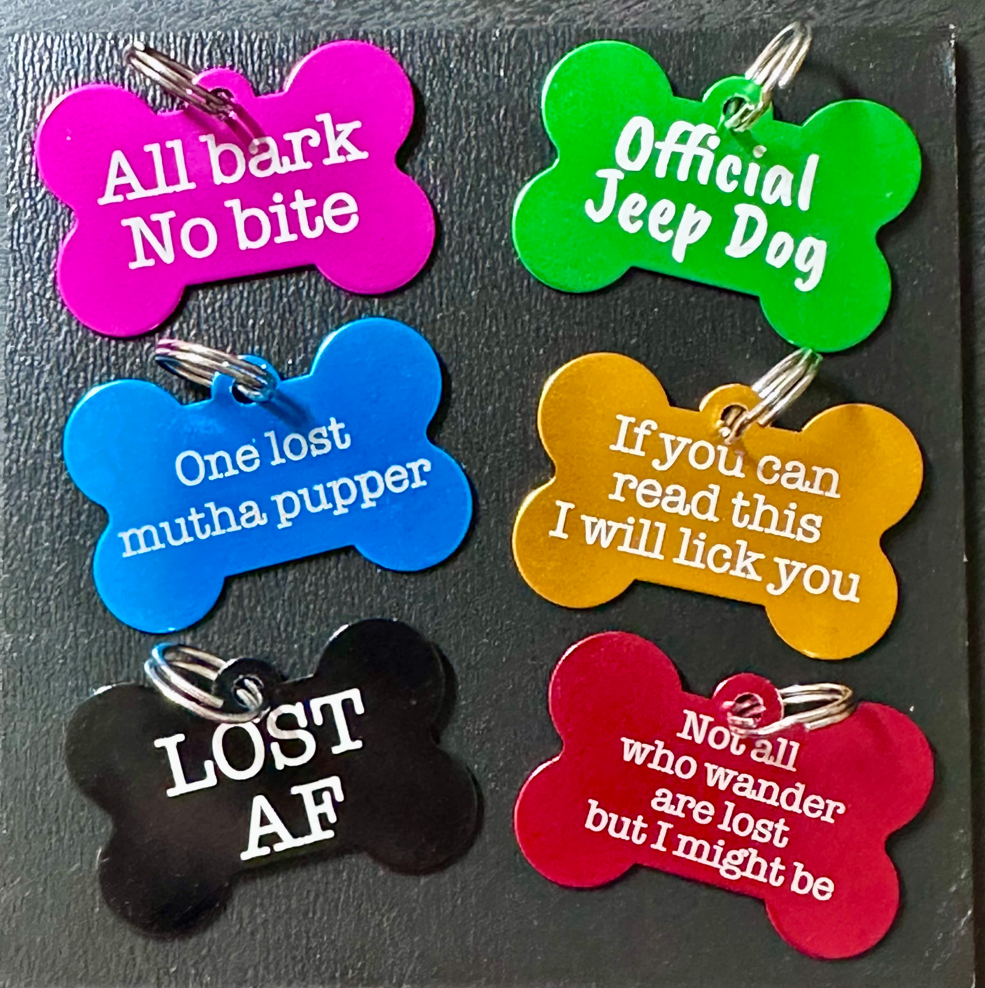Six colorful engraved bone-shaped pet ID tags with funny sayings