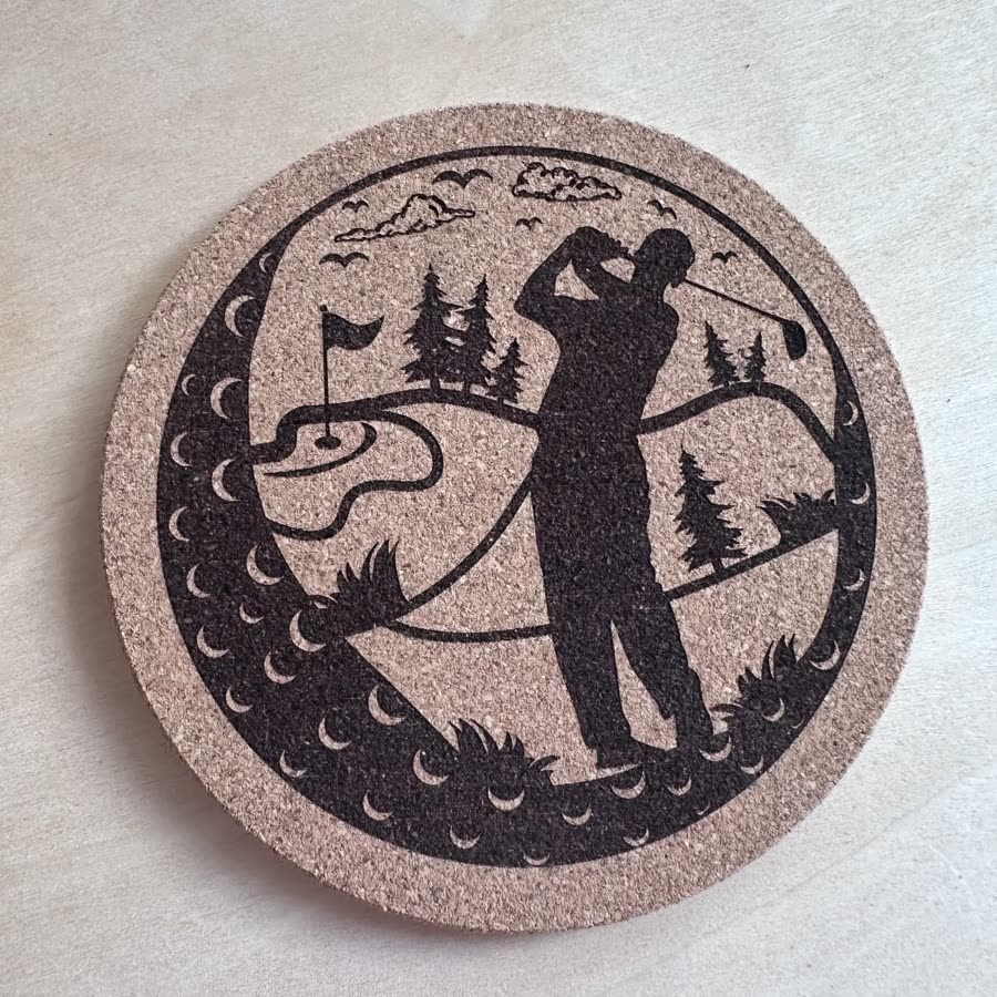 Round cork coaster engraved with a golfer mid-swing on a course